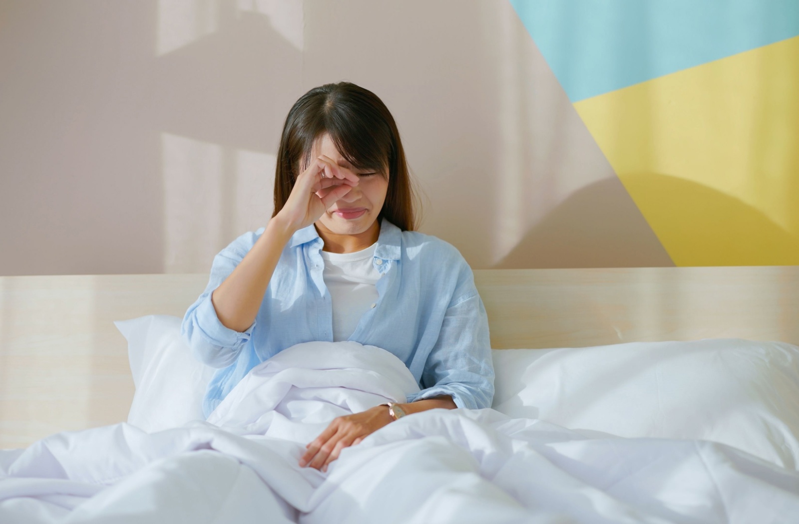 A person in bed waking up with dry irritated eyes.